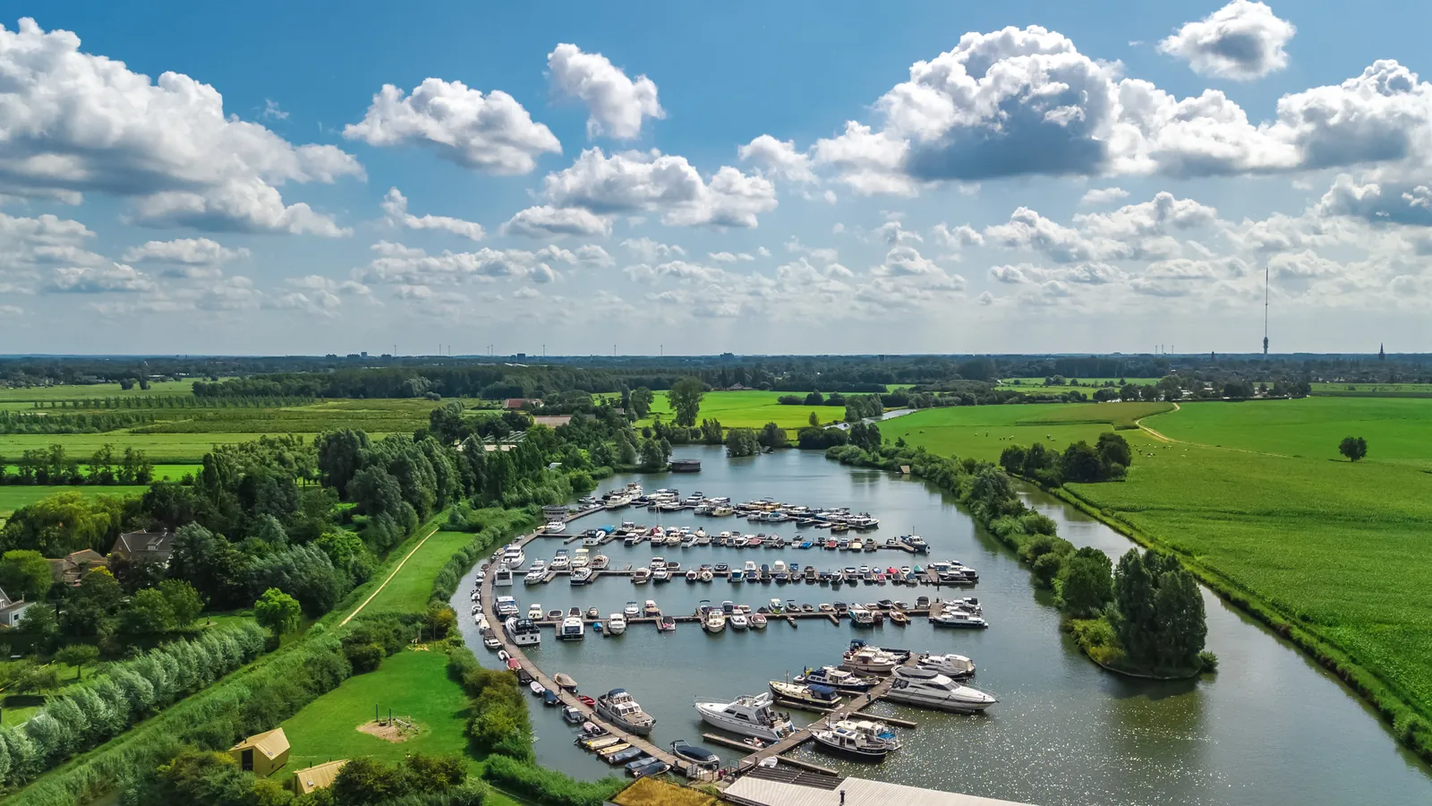 Luchtfoto van een jachthaven met boten en groene oevers in Noord-Holland.