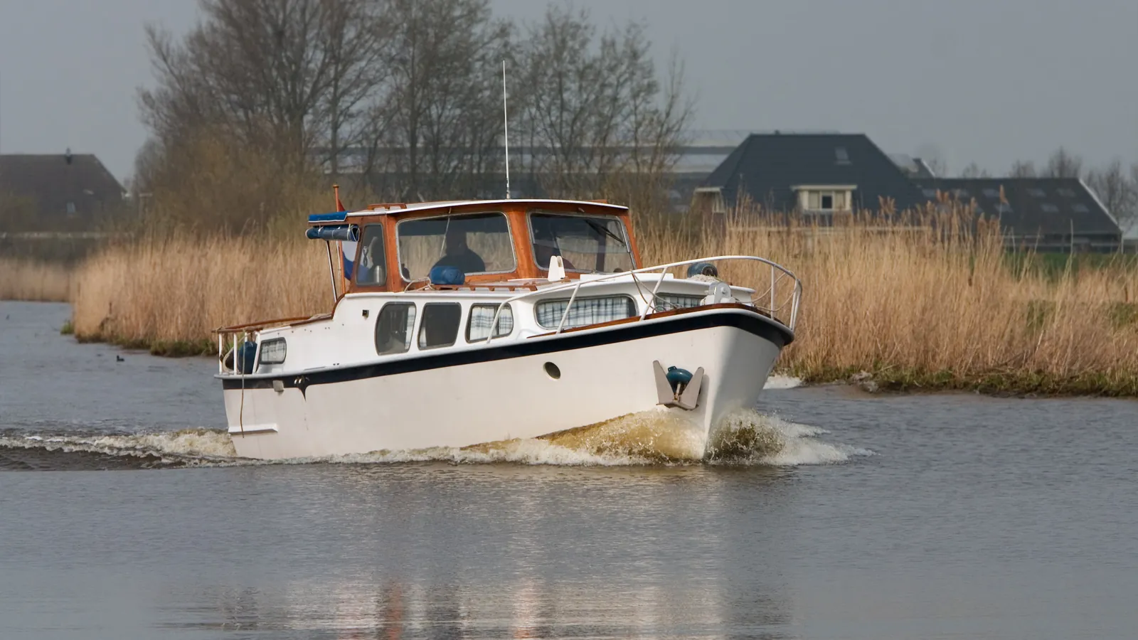 Motorboot vaart op de Eem langs rietkragen.