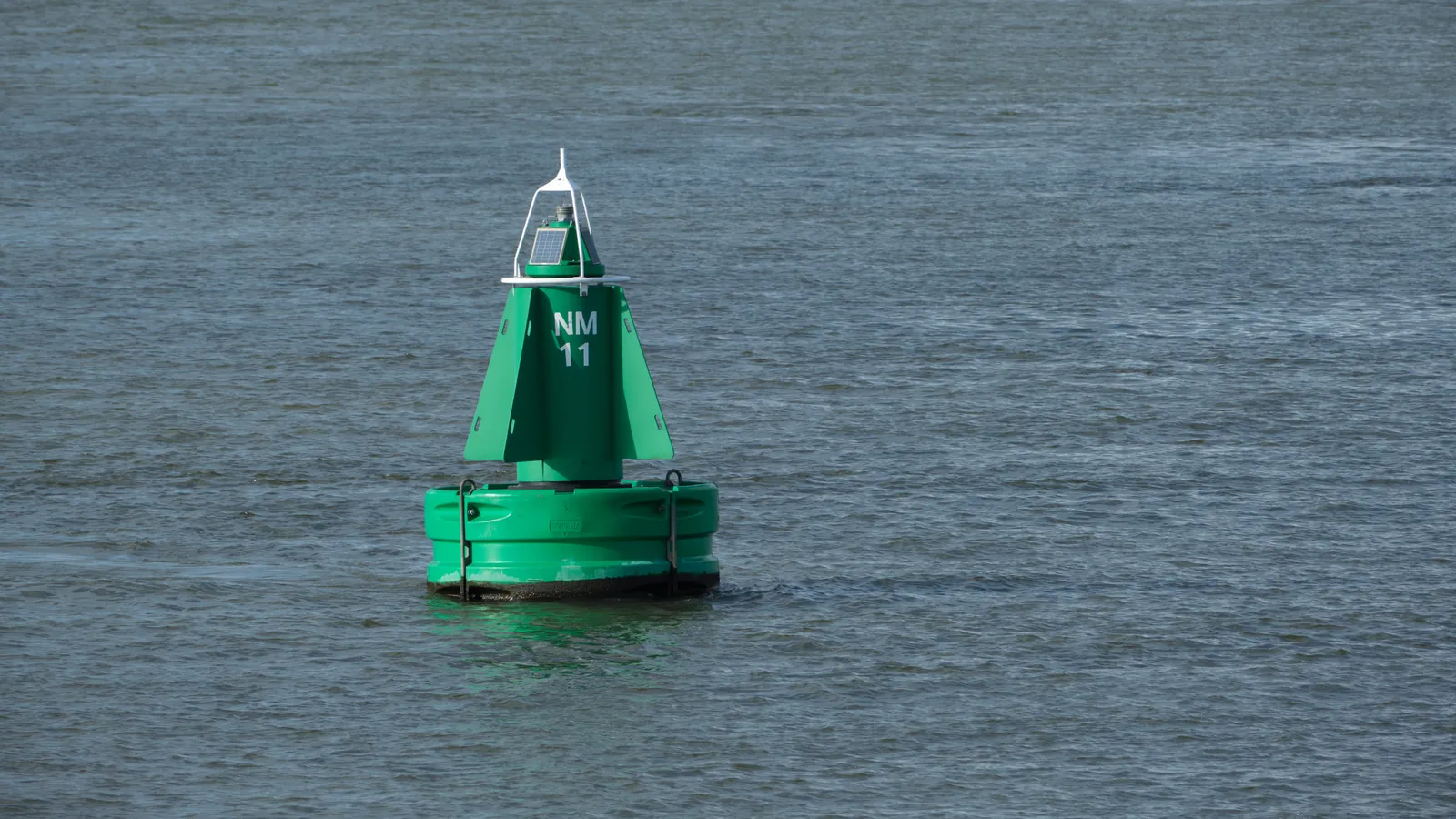 Groene vaarwegboei op het water bij Rotterdam.